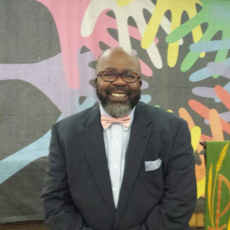 LJ Mitchell, in a suit, smiling at the camera