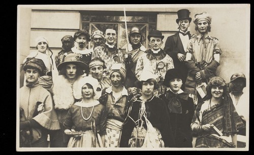 Download the full-sized image of People gathered outside a building wearing various costumes, some in drag. Photographic postcard, 1924.