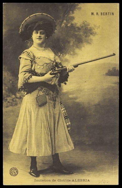 Download the full-sized image of Robert Bertin in drag as Clotilde Alégria, posing with a gun. Process print, 191-.