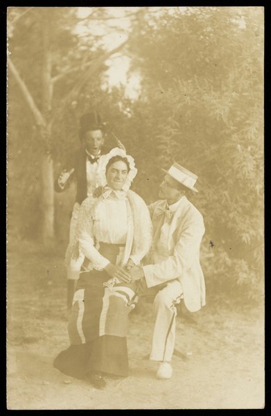 Download the full-sized image of Three actors, one in drag, posing in a tableau. Process print, 191-.