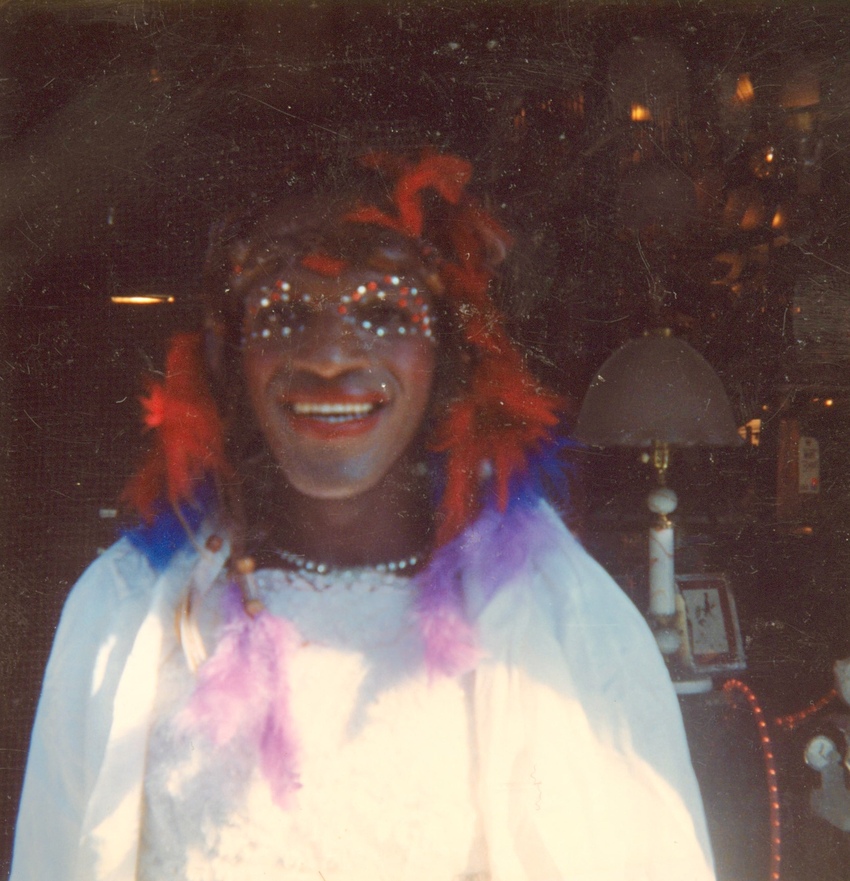Download the full-sized image of A Photograph of Marsha P. Johnson in a White Dress With Feathers in Her Hair and Gems Around Her Eyes