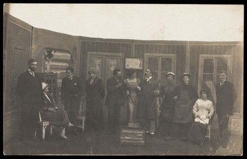 Download the full-sized image of French prisoners of war, some in drag, in a performance of "Les maris de Léontine" at Sennelager prisoner of war camp in Germany. Photographic postcard, 1918.