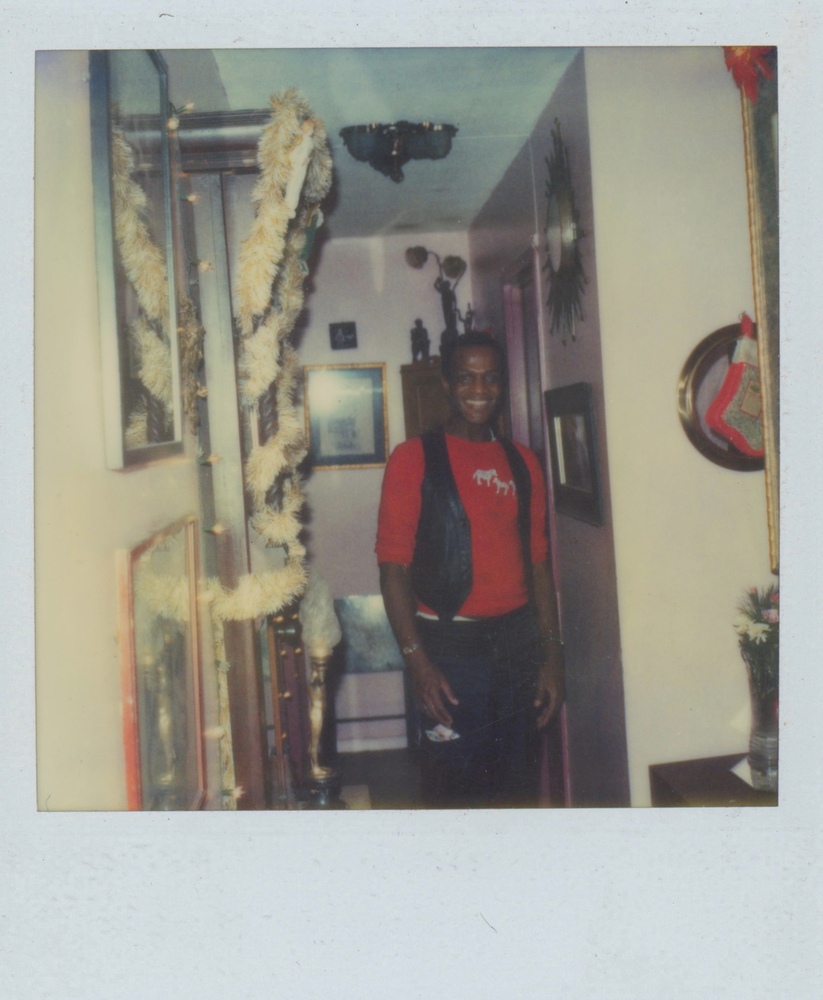 Download the full-sized image of A Photograph of Marsha P. Johnson Smiling in an Apartment with Christmas Decorations