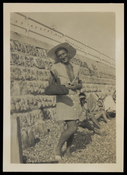 Download the full-sized image of A man in drag poses on a beach. Photograph, 1949.