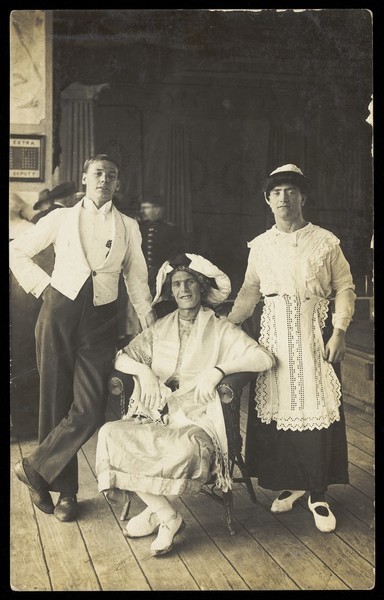 Download the full-sized image of Three soldiers, two in drag, pose in costume. Photographic postcard, ca. 1920.
