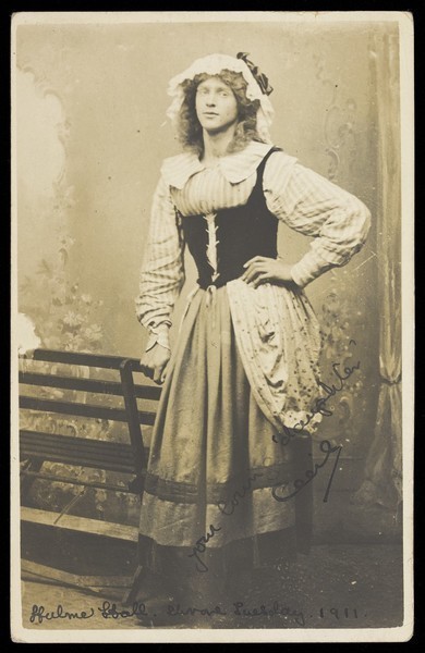 Download the full-sized image of Maitland Cecil Melville Wills, in drag, posing in a black corset and heavy skirt; on Shrove Tuesday 1911. Photographic postcard, 1911.