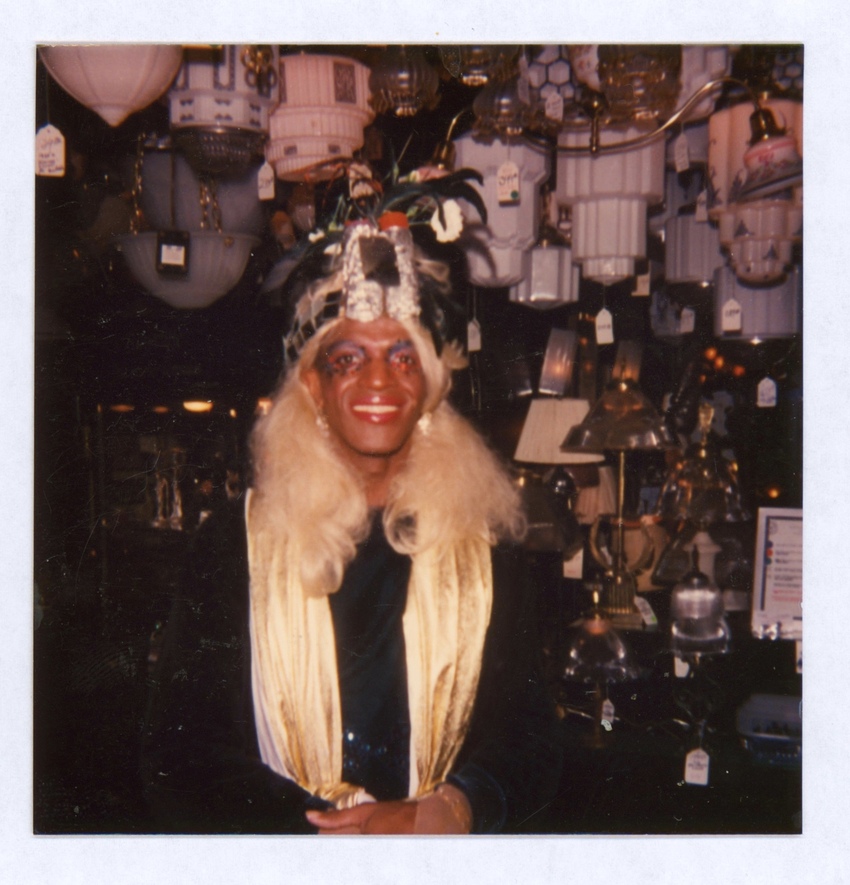 Download the full-sized image of A Photograph of Marsha P. Johnson with Blonde Hair, a Black Bejeweled Headpiece and Gold Scarf at Uplift Lighting