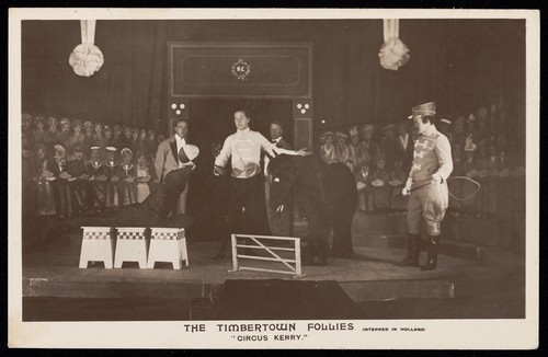 Download the full-sized image of British prisoners of war performing a circus act for "The Timbertown Follies", at a prisoner of war camp in Groningen. Photographic postcard, 191-.
