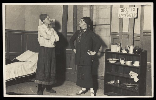 Download the full-sized image of Two amateur actors, both in drag, confront each other on stage. Photographic postcard, ca. 1918.