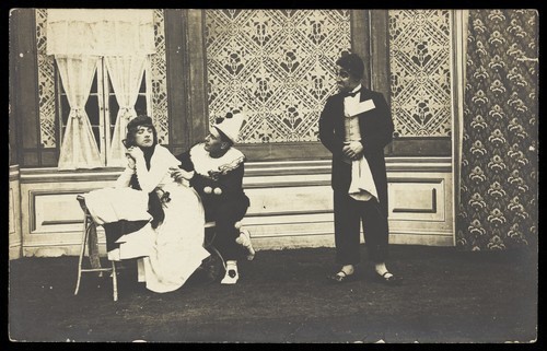 Download the full-sized image of Three men performing a scene from a play. Photographic postcard. 191-.