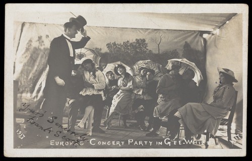 Download the full-sized image of Amateur actors, some in drag, pose on stage in "Gee-Whizz". Photographic postcard, 1917.