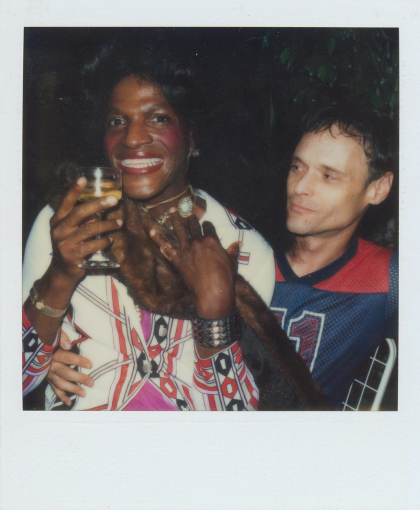 Download the full-sized image of A Photograph of Marsha P. Johnson Holding a Glass and a Fur Scarf While Sitting on Someone's Lap