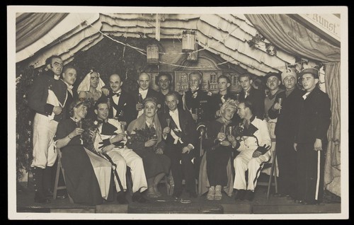 Download the full-sized image of German actors, some in drag, gather on stage at a party. Photographic postcard, 1930-45.