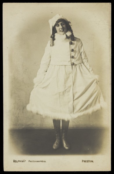 Download the full-sized image of An actor in drag, wearing a white fluffy-trim coat. Photographic postcard by Relph, ca. 1917-1918.
