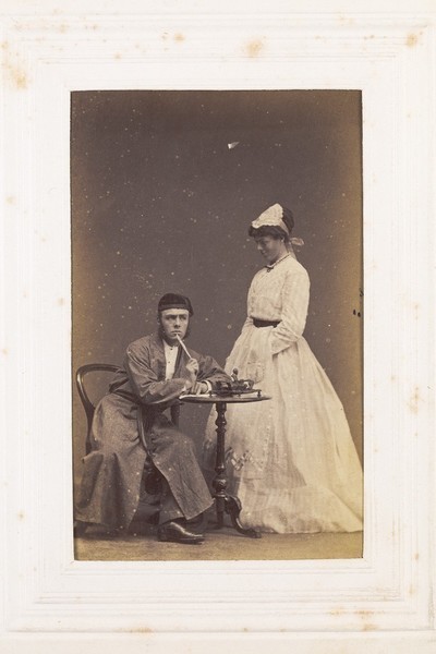 Download the full-sized image of Two men, one in drag, acting out a scene. Photograph, 189-.
