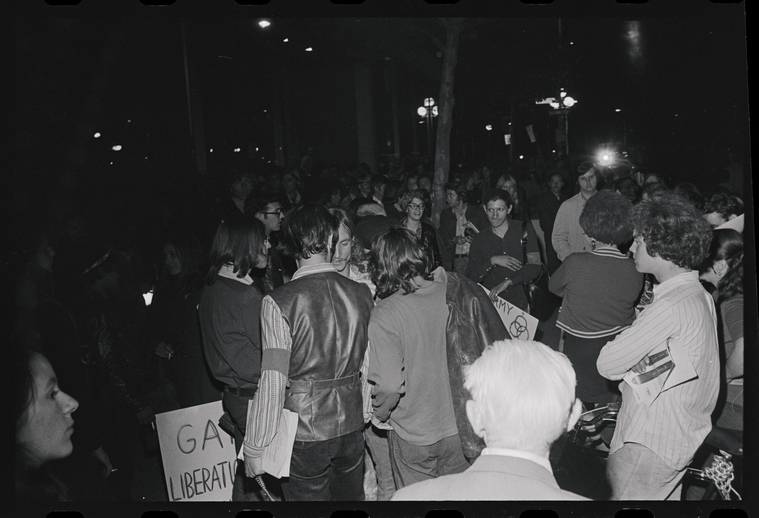 Download the full-sized image of A Nighttime Photograph of Protestors Talking as Sylvia Rivera Holds a Sign in the Background