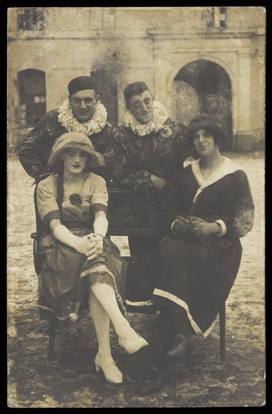 Download the full-sized image of Members of 'The Stars' concert party, two soldiers in drag and two as pierrots, pose around a bench. Photographic postcard, 1919.