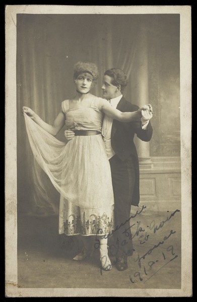 Download the full-sized image of Two actors, one in drag, dancing together on stage. Photographic postcard, 1918.