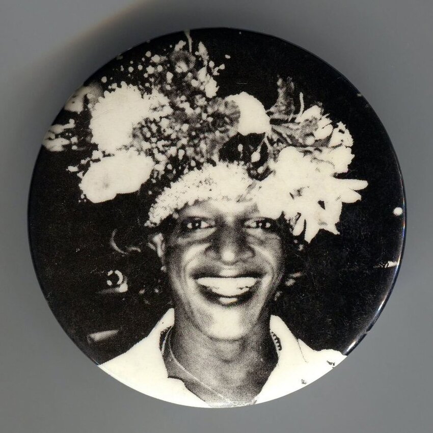 Download the full-sized image of A Pin of Marsha P. Johnson Wearing an Elaborate Flower Headpiece and Smiling