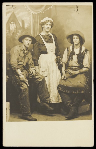 Download the full-sized image of Three actors, two in drag, posing in cowboy costumes. Photographic postcard, 1911.