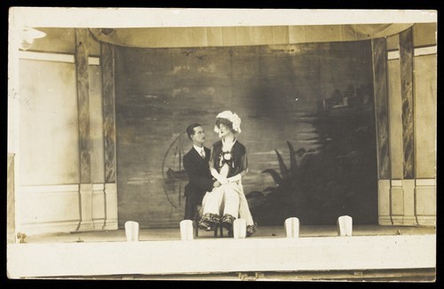 Download the full-sized image of Two men seated together on stage. Photographic postcard, 191-.